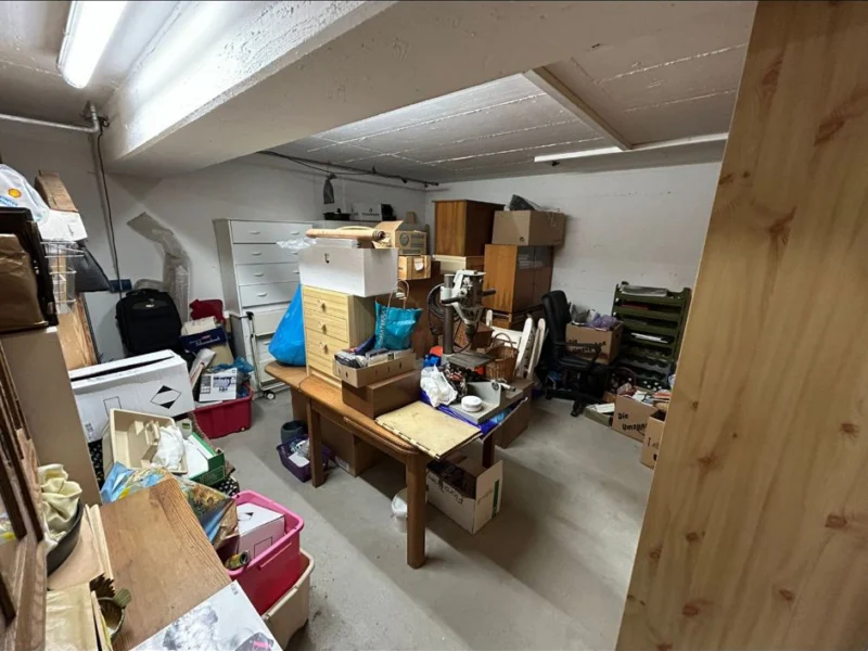 Kellerraum mit Kommode, Tisch, Kisten und Kartons vor der Räumung