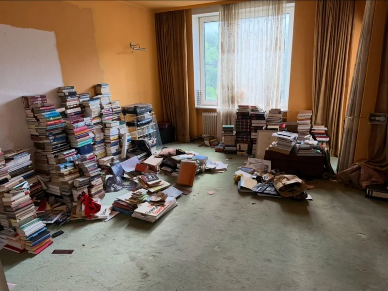 Zimmer mit deckenhohen Bücherstapeln auf dem Boden vor einer Kompletträumung