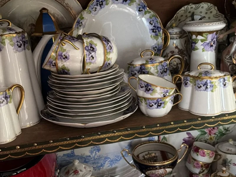 Vitrine mit Porzellanservice, Tellern, Tassen und Figuren