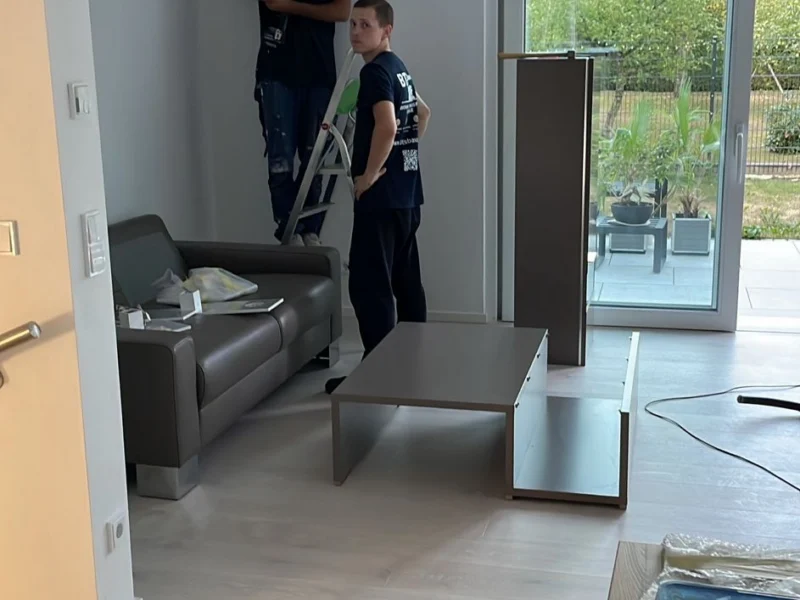 Zwei Mitarbeiter richten einen leeren Wohnraum für den Umzug