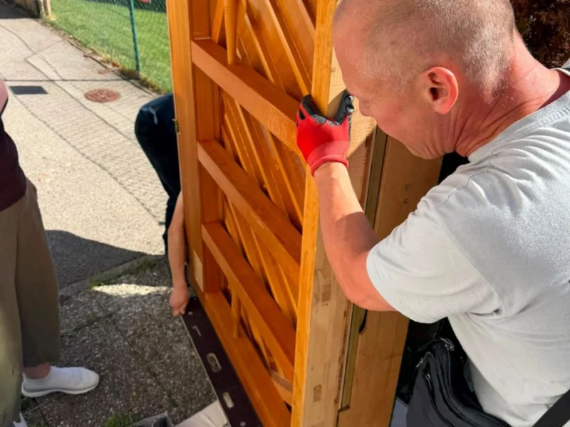 Zwei Mitarbeiter tragen einen Holzschrank aus dem Haus