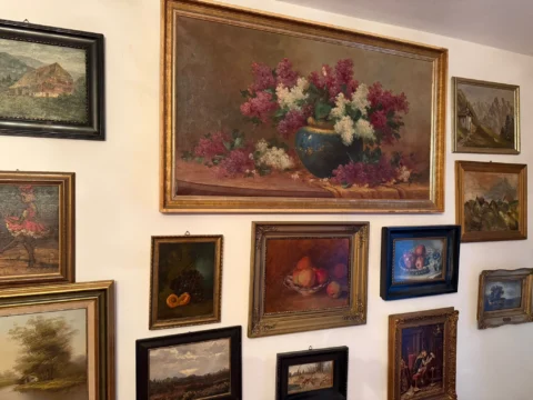 Wand mit gerahmten Ölgemälden, Blumenstillleben in der Mitte