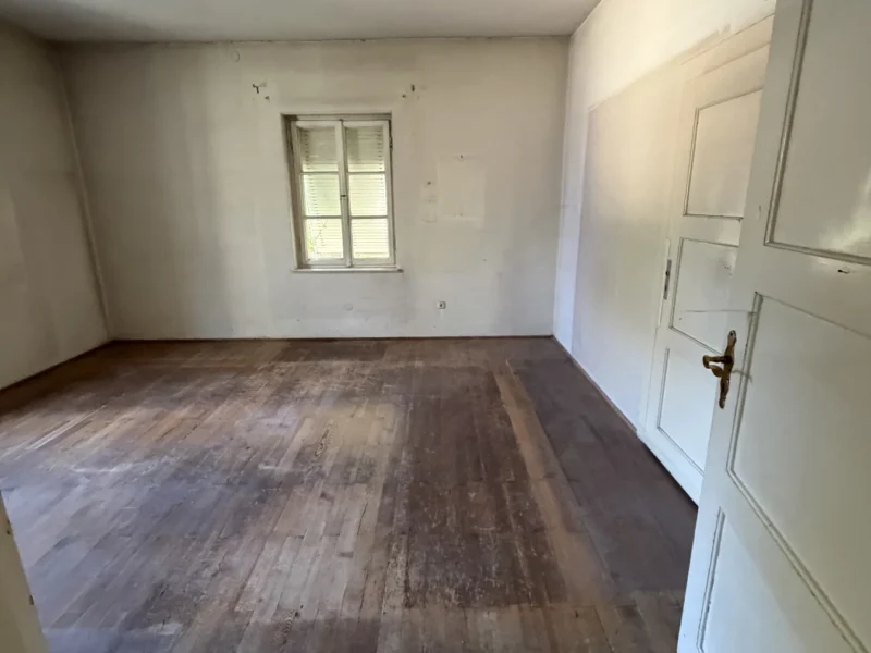 Geräumter Wohnraum nach der Entrümpelung in München-Neuhausen, mit freiem Holzboden und sichtbaren Wandflächen.